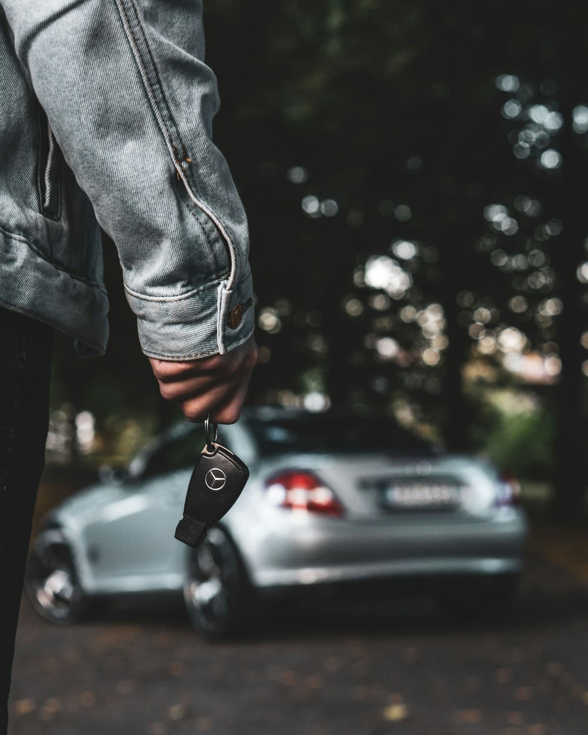 A person holding a car key beside their car