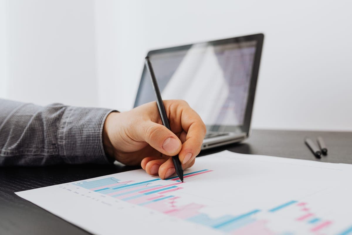 Annotating a financial chart beside a laptop