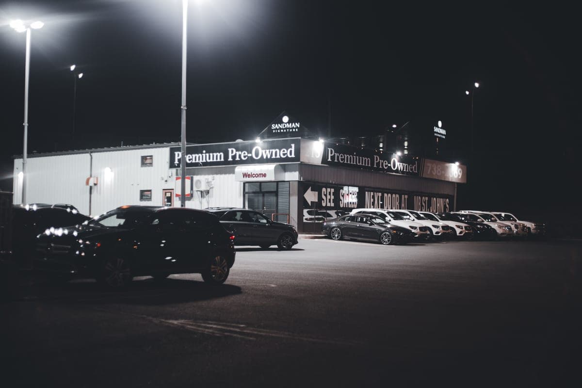 A dealership lot at night with cars lined up