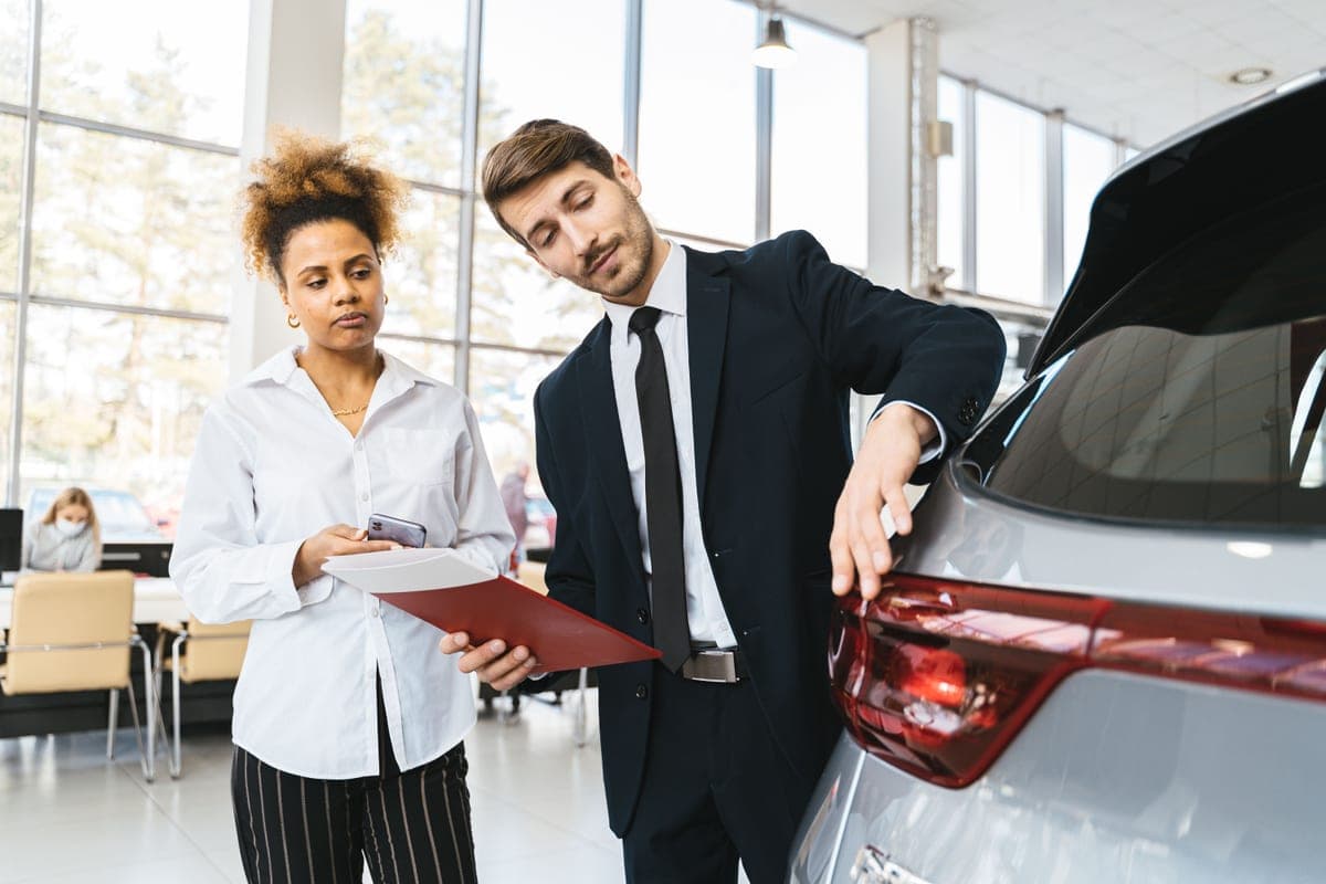 A sales consultant explaining a car to a customer in a showroom